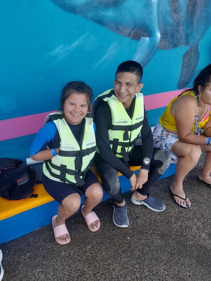 Dos jóvenes sonríen sentados con sus trajes de neopreno después de la terapia